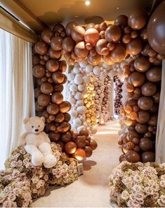 there is a teddy bear sitting in the middle of this balloon arch with balloons all over it