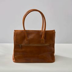 The Antonella Tote Bag is a office-appropriate carryall and that 'something sleek' for your 9-to-5 routine. The stunning cognac leather will develop an authentic patina over time, making it even more luxurious looking. Comes with Hektor + Helena's Lifetime warranty and guarantee. Made of Italian vegetable tanned leather, our bags are all handmade by master craftsmen who have been perfecting their skills for generations. The result is a striking blend of rich earth-toned colors, providing a glowi Elegant Brown Weekender Bag For On-the-go, Luxury Cognac Weekender Bag For Everyday, Dark Tan Rectangular Satchel For Travel, Dark Tan Rectangular Travel Satchel, Brown Bags With Leather Handles For Workwear, Classic Dark Tan Bags For Daily Use, Leather Weekender Bag In Cognac For Everyday, Classic Cognac Tote Weekender Bag, Cognac Satchel Bag For Everyday Use