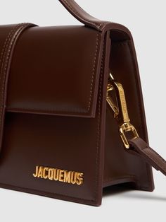 Height: 13cm Width: 23.5cm Depth: 6cm. Strap drop: 45cm. Handle drop: 4cm. Detachable strap. Single top handle. Front flap closure. Metal logo detail. Lined Jacquemus Bambino, Jacquemus Le Bambino Long, Structured Bag, Brown Leather Shoulder Bag, Small Shoulder Bag, Metallic Logo, Small Leather Goods, Flap Bag, Belt Bag