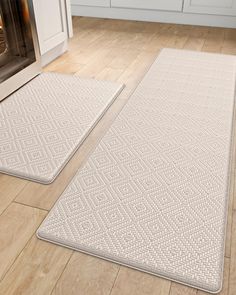 two white rugs sitting on top of a wooden floor next to an oven in a kitchen