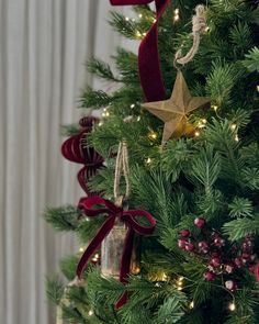 a christmas tree decorated with red ribbon and gold star ornament hanging from it