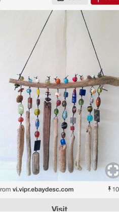 a mobile with beads and wooden sticks hanging from it's side on a white wall