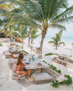 a woman sitting at a table on the beach