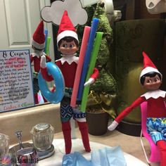 two elfs are sitting on the bathroom sink with toothbrushes in their hands