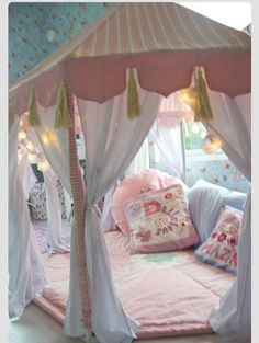 a canopy bed with curtains and pillows in a room that looks like a princess's bedroom