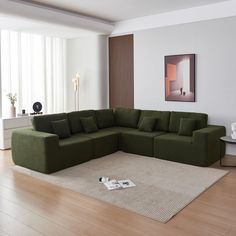 a large green couch sitting on top of a wooden floor next to a white rug