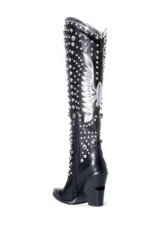 The Upbeat Western Boot In Black is made from a faux leather fabrication and features rhinestone gems in varying sizes, a metallic, rounded collar, a knee-high shaft, Western-inspired patch and stitch detailing, a pointed toe silhouette, a chunky heel, and an inner ankle zipper closure. Feel like a star at any music festival or concert! Faux leather upper Pointed toe Chunky heel 21” shaft height 4.25” heel height Black Boots With Rhinestone Rivets For Winter, Black Winter Boots With Rhinestone Rivets, Embellished Black Heeled Boots For Winter, Black Western Boots With Rhinestone Rivets, Leather Boots With Rhinestones For Fall, Black Rhinestone Boots For Fall, Embellished Black Heeled Boots For Fall, Black Embellished Heeled Boots For Fall, Leather Heeled Boots With Rhinestones And Round Toe