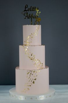 a three tiered wedding cake with gold confetti on the top and bottom