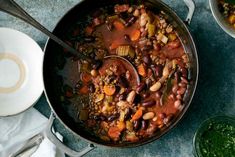 a pot filled with beans and vegetables next to other dishes on the table, ready to be eaten