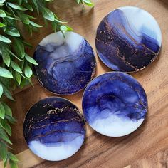 three blue and white plates sitting on top of a wooden table next to a potted plant