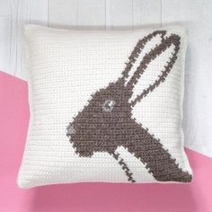 a crocheted pillow with a brown and white rabbit on it's side