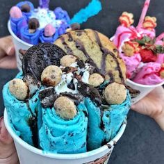 three ice cream cones with chocolate, cookies and sprinkles in them are being held by two hands