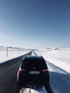 a car parked on the side of a road in the middle of snow covered ground