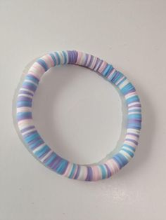 a close up of a bracelet on a white surface with blue, pink and purple stripes