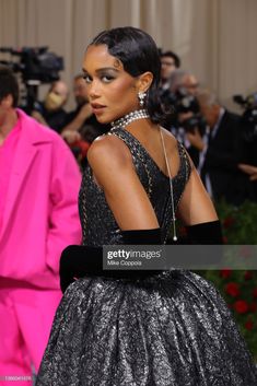 the back of a woman's dress as she walks down the red carpet at the met