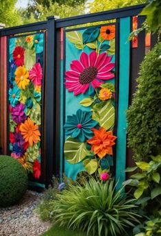 colorful flowers are painted on the side of a fence with grass and bushes around it