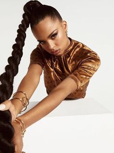 a woman sitting on top of a white box holding her hair in one hand and looking at the camera