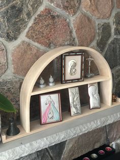 there is a shelf with pictures and other items on it in front of a stone wall