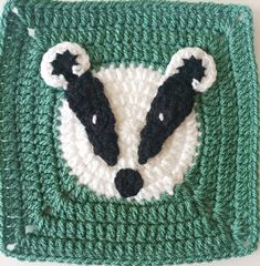 a crocheted square with two black and white raccoon heads on it