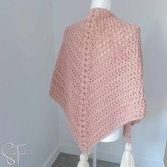 a pink crocheted shawl draped over a mannequin