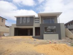 a two story house under construction in the middle of a dirt lot with no grass