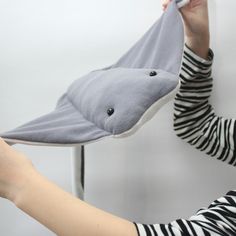 a woman holding up a stuffed shark toy