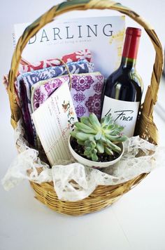 a wicker basket filled with wine, books and succulents next to a bottle of wine