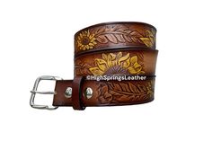 * Hand Painted Sunflower embossed brown leather belt with name laser engraved free on center back (visible) for Men and Women * Beautiful sunflower design with feathers * Painting is done in the dyeing process and sealed, the paint will not rub off * Please specify font number next to your name, if no font specified we will use 1707C * Made in High Springs, Florida  * 9 to 10 oz (3.5mm) thick one piece full grain vegetable tanned cowhide leather * Snap, Buckle closure so you can easily change bu Adjustable Engraved Leather Belt, Western Style Engraved Leather Belt, Western Style Brown Belt With Engraving, Sunflower Leather Belt, High Springs Florida, Feathers Painting, Artisan Brown Embroidered Belt, One Piece Full, Font Number