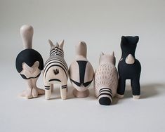 five wooden cats sitting next to each other in front of a white background and one cat with black hair