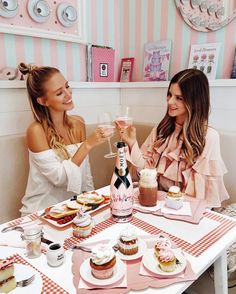 two women sitting at a table with desserts and drinks