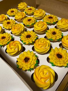 cupcakes decorated with yellow frosting and sunflowers are in a box