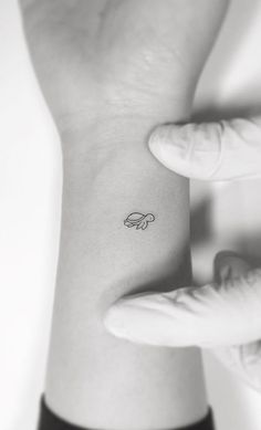 a person's wrist with a small tattoo on the left side of their arm