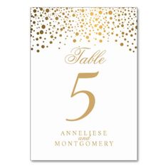 a table number card with gold confetti on white paper and the number five