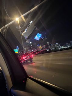 the view from inside a car at night with city lights and buildings in the background