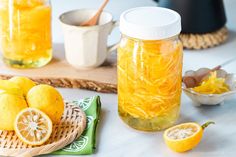 two jars filled with lemonade sitting on top of a table next to sliced lemons