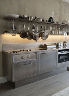 an industrial style kitchen with stainless steel appliances and cooking utensils on the wall