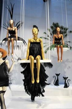 three mannequins in black and white dresses hanging from strings