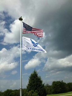 two american and u s air force flags flying in the wind on a cloudy day