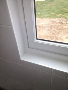 an open window in the corner of a room with white walls and tile flooring