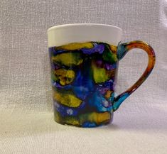 a colorful coffee cup sitting on top of a white table