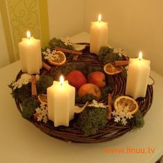 a wicker tray with candles and fruit in it on top of a white table