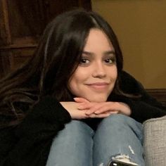 a woman sitting on top of a gray couch