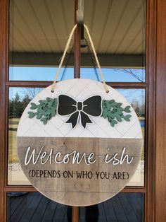 a welcome sign hanging from the front door of a building with a bow on it that says, welcome - ish defends who you are