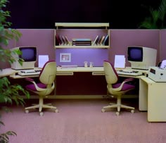 an office cubicle with three computer screens and two desks, one on top of the other