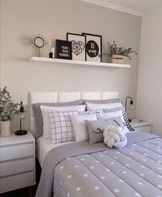 a bed with pillows and blankets on top of it next to a white dresser in a bedroom