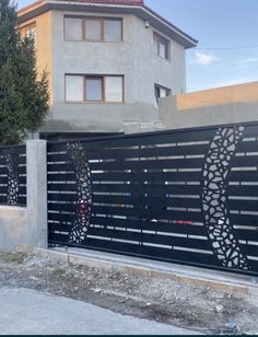 a black and white gate in front of a house with an artistic design on it