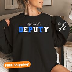 Celebrate the strength and dedication of deputy wives with our Deputy Wife Sweatshirt, a perfect Police Officer Gift. Crafted with comfort in mind, this custom sweatshirt is designed for both him and her, making it an ideal Couples Gift. Show your pride in the Thin Blue Line community with the K9 Police Sweatshirt, a personalized and thoughtful engagement gift for the police officer in your life. Whether it's for Mothers Day or any occasion, this sweatshirt is a stylish and meaningful way to honor the commitment of law enforcement families. About this sweatshirt: - 50% cotton, 50% polyester - Medium-heavy fabric (8.0 oz/yd² (271.25 g/m - Loose fit - Runs true to size - No hood   Sizing details:  - We offer unisex sizing for all tees & sweatshirts. - Our Sweatshirts run about 1 size larger Law Enforcement Family, Deputy Wife, K9 Police, Wife Sweatshirt, Police K9, Police Officer Gifts, Police Wife, Couples Gift, Custom Sweatshirts