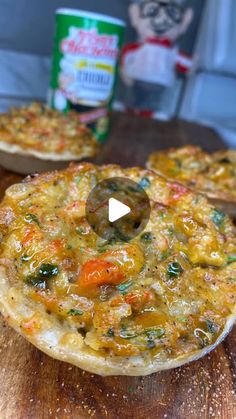 two pizzas sitting on top of a wooden cutting board next to a can of cat food