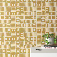 the wallpaper is yellow and has white squares on it, as well as a potted plant