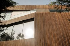 the side of a wooden building with large windows